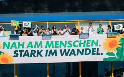 Menschen jubeln hinter einem Banner mit der Aufschrift "Nah am Menschen, stark im Wandel"