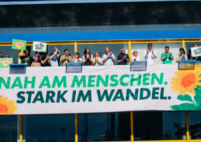 Menschen jubeln hinter einem Banner mit der Aufschrift "Nah am Menschen, stark im Wandel"